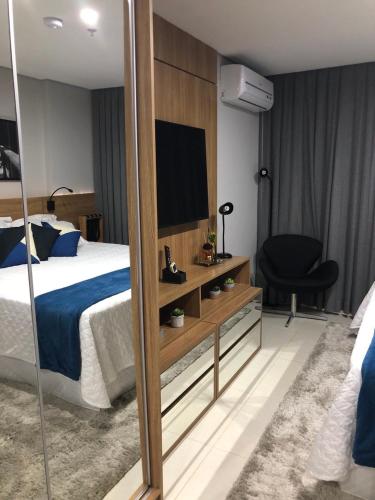 a hotel room with a bed and a television at Charmoso Flat em Itaipava, 509 Mangabeiras. in Petrópolis