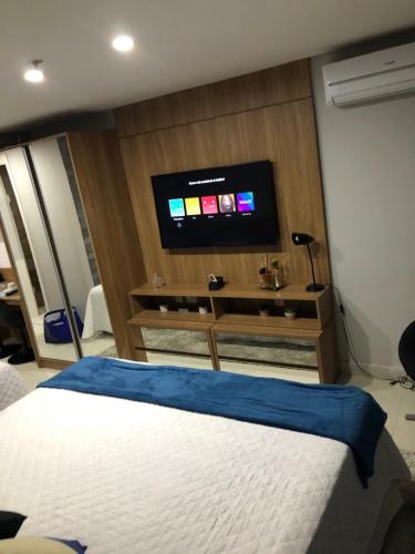 a bedroom with a bed and a flat screen tv at Charmoso Flat em Itaipava, 509 Mangabeiras. in Petrópolis