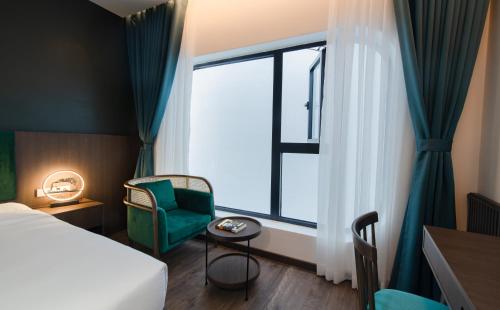 a hotel room with a bed and a chair and a window at Khách sạn gần biển Miami Tuy Hoà Phú Yên in Liên Trì (3)