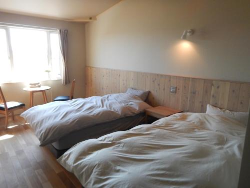 2 Betten in einem kleinen Zimmer mit Fenster in der Unterkunft Meiji no Okano Yado in Biei