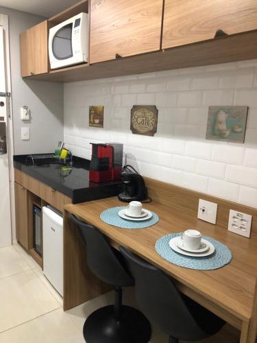 a kitchen with a table with two cups and plates on it at Charmoso Flat em Itaipava, 509 Mangabeiras. in Petrópolis
