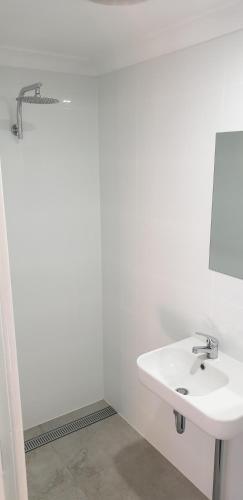 a white bathroom with a sink and a shower at Green Head Caravan Park in Green Head
