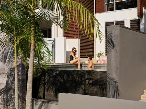 a woman and child sitting on the edge of a swimming pool at RACV Noosa Resort in Noosa Heads
