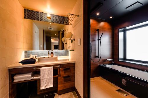 a bathroom with a sink and a tub and a mirror at PROSTYLE TERRACE NAHA in Naha