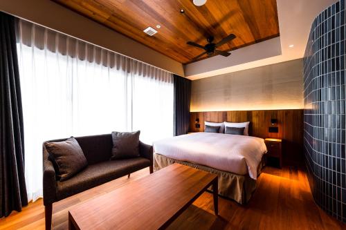 a hotel room with a bed and a couch at PROSTYLE TERRACE NAHA in Naha