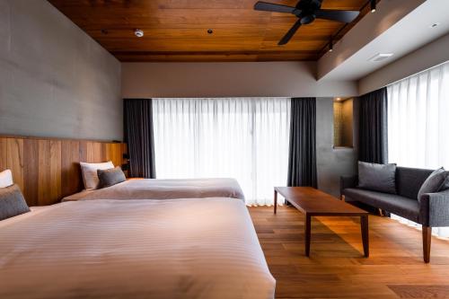 a hotel room with two beds and a chair at PROSTYLE TERRACE NAHA in Naha