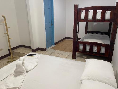 a bedroom with a bed and two bunk beds at La Hacienda Rooms & Food in Jacó