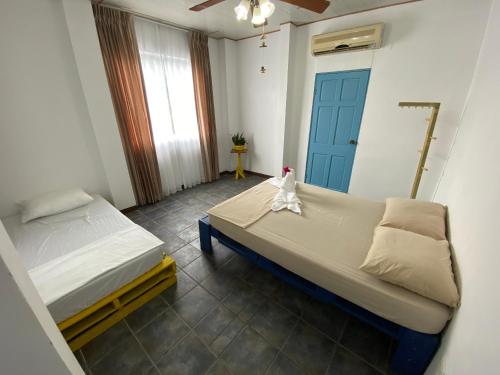 a bedroom with two beds and a blue door at La Hacienda Rooms & Food in Jacó