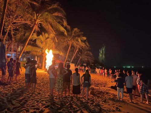 a group of people standing around a bonfire on a beach at Orange Resort in Phu Quoc