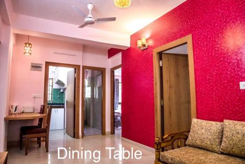 uma sala de estar com uma parede vermelha e um sofá em Ruby by Olys Apartment em Calcutá