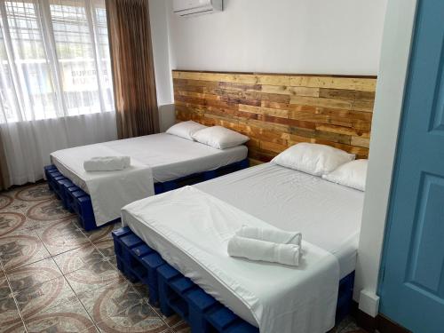 a room with two beds and a blue door at La Hacienda Rooms & Food in Jacó