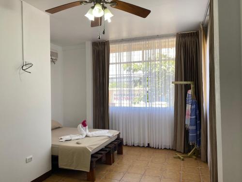 a room with a bed and a ceiling fan at La Hacienda Rooms & Food in Jacó