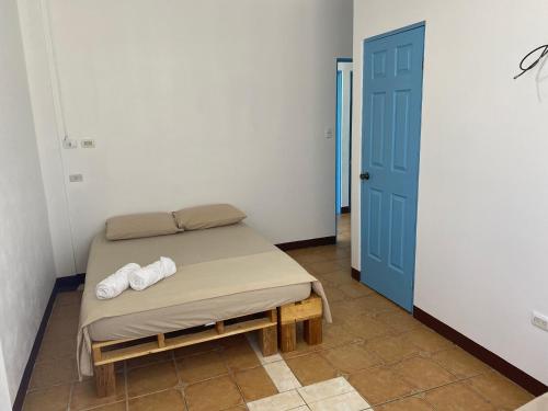 a small bed in a room with a blue door at La Hacienda Rooms & Food in Jacó
