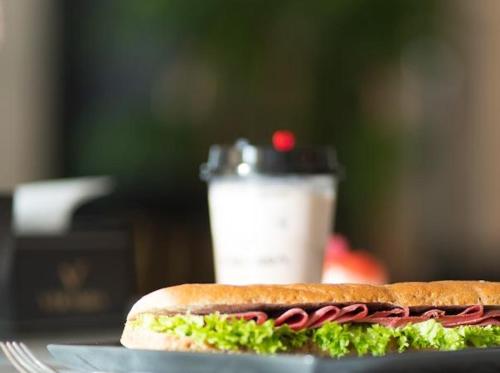 a sandwich on a plate next to a drink at Alwadaq Hotel in Taif