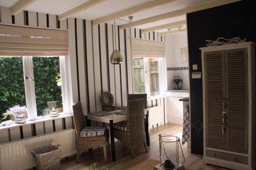 een eetkamer met een tafel, stoelen en ramen bij Summerhouse Zandvoort in Zandvoort