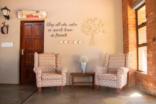 twee stoelen en een tafel met een bord aan de muur bij Bel Tramonto in Bloemfontein