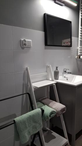 baño con lavabo y silla con espejo en Avalon apart 1 en Legnica