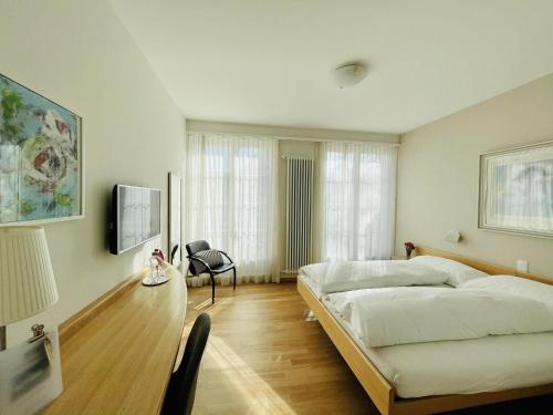 a bedroom with a bed and a chair and a tv at Hotel Rössli in Basel
