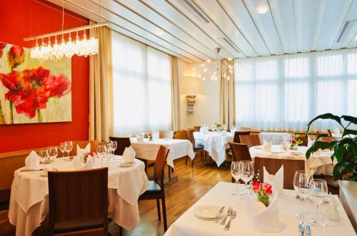 a restaurant with white tables and chairs and windows at Hotel Rössli in Basel