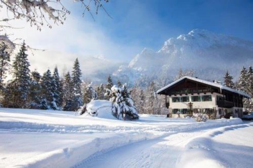 een met sneeuw bedekte hut met een berg op de achtergrond bij Flinsenlehen in Schönau am Königssee