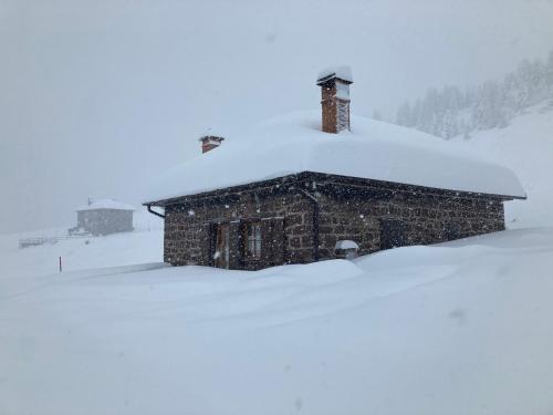a snow covered building with a chimney on top of it at Baita Casera Caviazza in Falcade