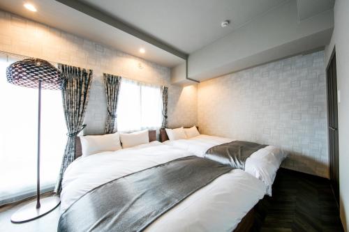 a bedroom with a large bed with white sheets at VILLA KOSHIDO kotoni in Sapporo