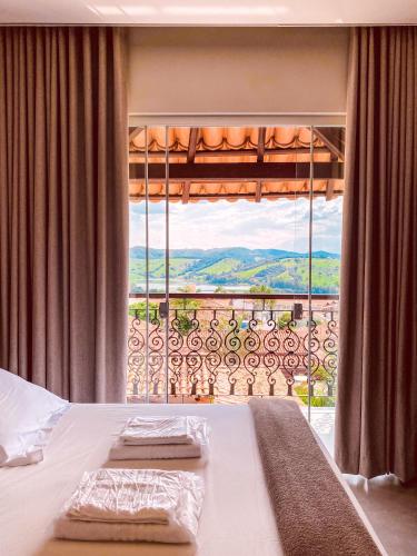a bedroom with a bed and a large window at Pousada Buena Vista in Capitólio