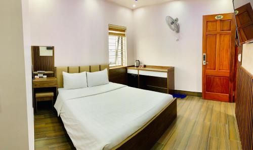 a bedroom with a bed and a desk and a door at MV Hotel in Hai Phong