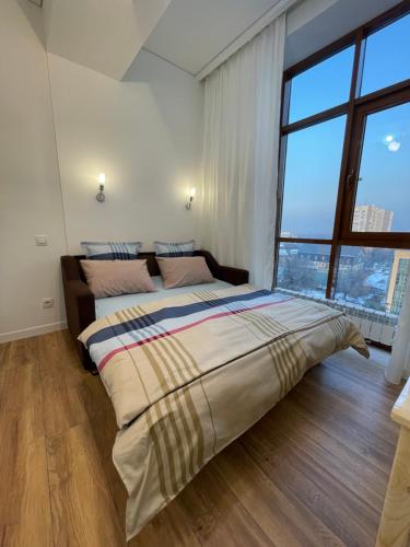 a bedroom with a large bed with a large window at Mini cozy corner #1 in Almaty