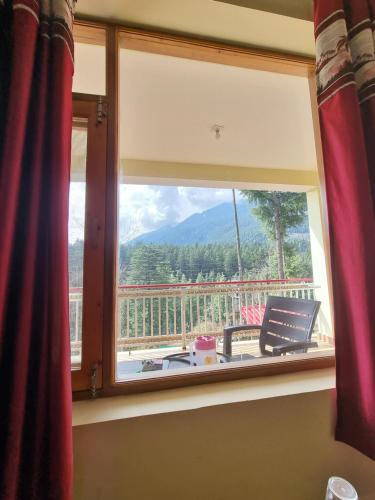a window with a view of a mountain view at Uncle Nomad in Manāli