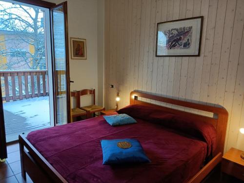 a bedroom with a bed with a purple blanket and a balcony at Bilocale Gran Chalet Montecreto in Montecreto