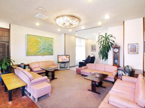 a waiting room with pink couches and a tv at Hotel Daikokuya in Yatsushiro