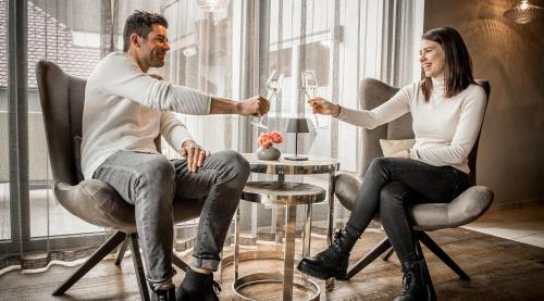 a man and woman sitting around a table with wine glasses at Hotel Restaurant Spa Torkel in Nonnenhorn