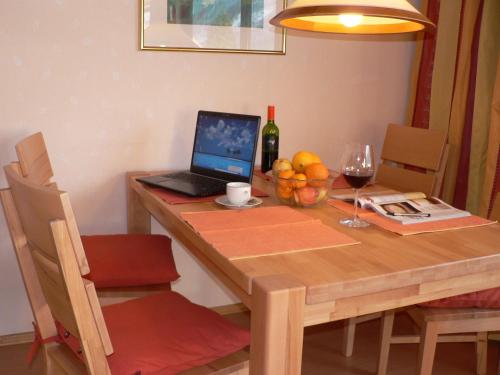 a wooden table with a laptop and a bowl of fruit at Antares am See in Maurach