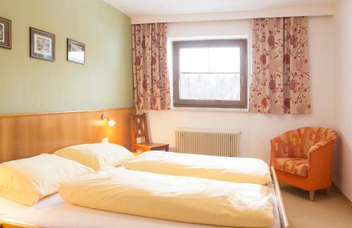 a bedroom with two beds and a chair and a window at Antares am See in Maurach