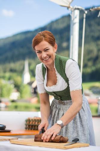 a woman is cutting food on a cutting board at Arlbergerhof Vital in Weissensee