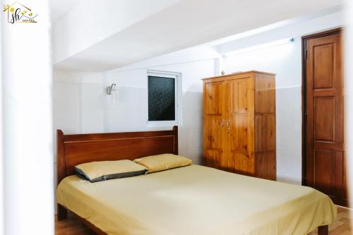 a bedroom with a bed and a wooden cabinet at SH Hotel in Hue
