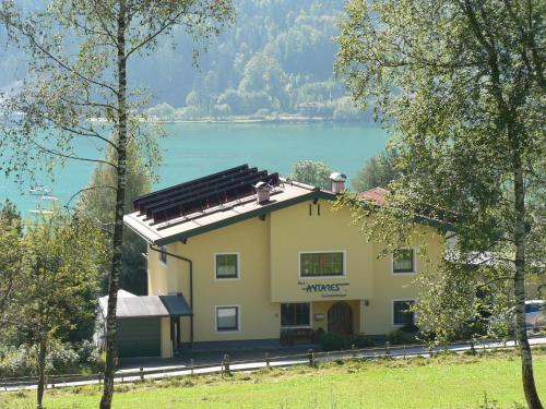 a yellow house with a lake in the background at Antares am See in Maurach