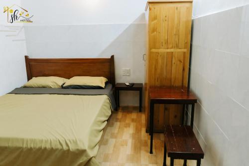 a bedroom with a bed and a wooden cabinet and a table at SH Hotel in Hue