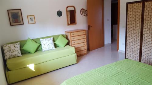 a living room with a green couch and a dresser at Villa Sogno sulla Spiaggia in Fontane Bianche