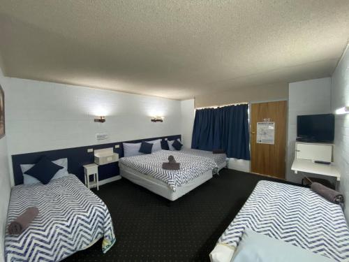 a hotel room with two beds and a television at Capri Motel in Balranald