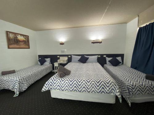 two beds in a room with blue and white sheets at Capri Motel in Balranald