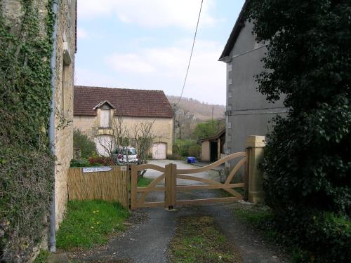 a wooden gate in a village with a fence at La Grange aux Roses in Tursac