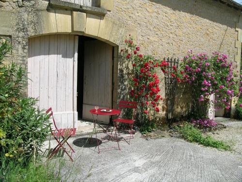 a table and chairs in front of a building with flowers at La Grange aux Roses in Tursac