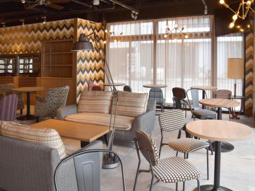 a restaurant with tables and chairs and windows at UMEDAHOLIC HOTEL in Osaka