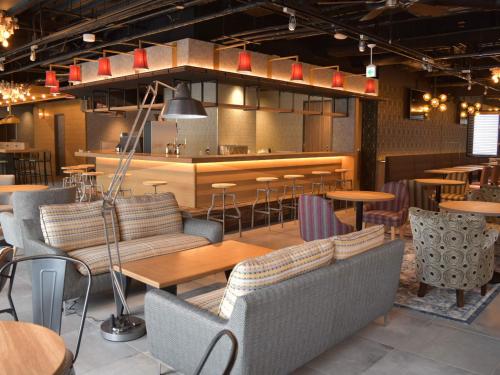 a restaurant with tables and chairs and a bar at UMEDAHOLIC HOTEL in Osaka
