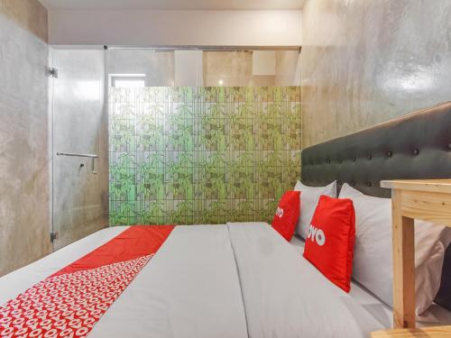 ein Schlafzimmer mit einem Bett mit roten Kissen und einer Dusche in der Unterkunft OYO 90305 De Umbrela Mansion Syari'ah Ciputat in Tangerang