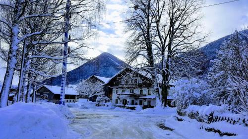 a house covered in snow with trees and mountains at Gasthof Tiroler Hof in Bad Feilnbach