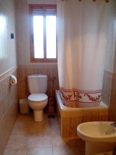 a bathroom with a toilet and a tub and a sink at Casa María Jesús in Pórtugos