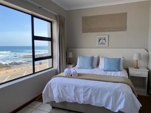a bedroom with a bed with a view of the ocean at Herolds Bay Accommodation - Smalstaan Upstairs in Herolds Bay